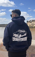 Modelo de espaldas con Hoodie Urban Essentials azul marino estampado coche clásico UrbanVibesX - sudadera streetwear UVX Studio